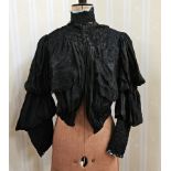 A black Victorian open-work skirt with pleated flounces and lace trim, the final flounce is