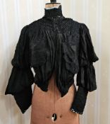 A black Victorian open-work skirt with pleated flounces and lace trim, the final flounce is