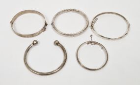 Four silver hinged bangles including two engraved, one faceted and the other with a ropetwist design