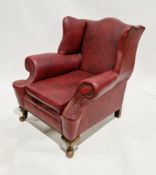Early 20th century wingback armchair, upholstered in a brass studded red leatherette, on front short