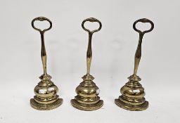 Three 19th century style brass doorstops or porters in the manner of William Tonks, with loop handle