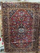 Iranian red ground Keshan wool rug with central geometric medallion on floral field, floral