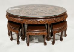 South East Asian hardwood nesting coffee table, the main table of oval form having relief carving