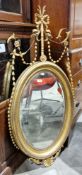 19th century gilt framed wall mirror in the Adam manner, with oval bevelled plate surmounted by