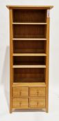 Modern pale oak bookcase with one fixed and three adjustable shelves, over a bank of four short