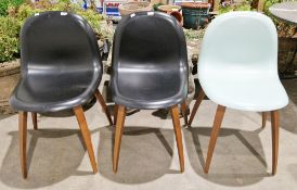 Three Gubi 5 dining chairs, two with black seats and one with a pale green finish, all on wooden