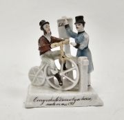 Late 19th century continental porcelain fairing, modelled with a gentleman on a bicycle beside