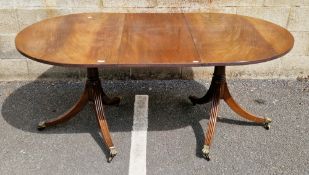 Mahogany twin-pillar extending dining table of Regency-style, rounded oblong, the top with reeded
