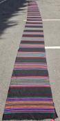 Very large black ground runner with multiple rows of red, yellow, blue stripes 945cm x 80cm