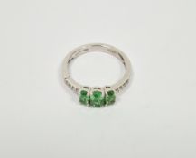 Lady's 18ct white gold dress ring set with three claw set peridots, flanked by four small diamonds