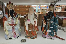 Three contemporary Chinese figures of immortals, each enriched in a bright palette and highlighted