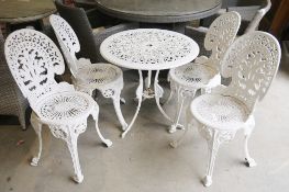 White painted circular garden table and matching chairs featuring intricate interlocking foliate
