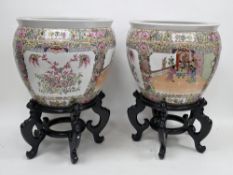 Pair of Chinese porcelain famille rose fish bowls on wooden stands, 21st century, printed iron red