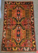 Baluchi red ground rug with two large geometric medallions, single floral border 140cm x 87cm