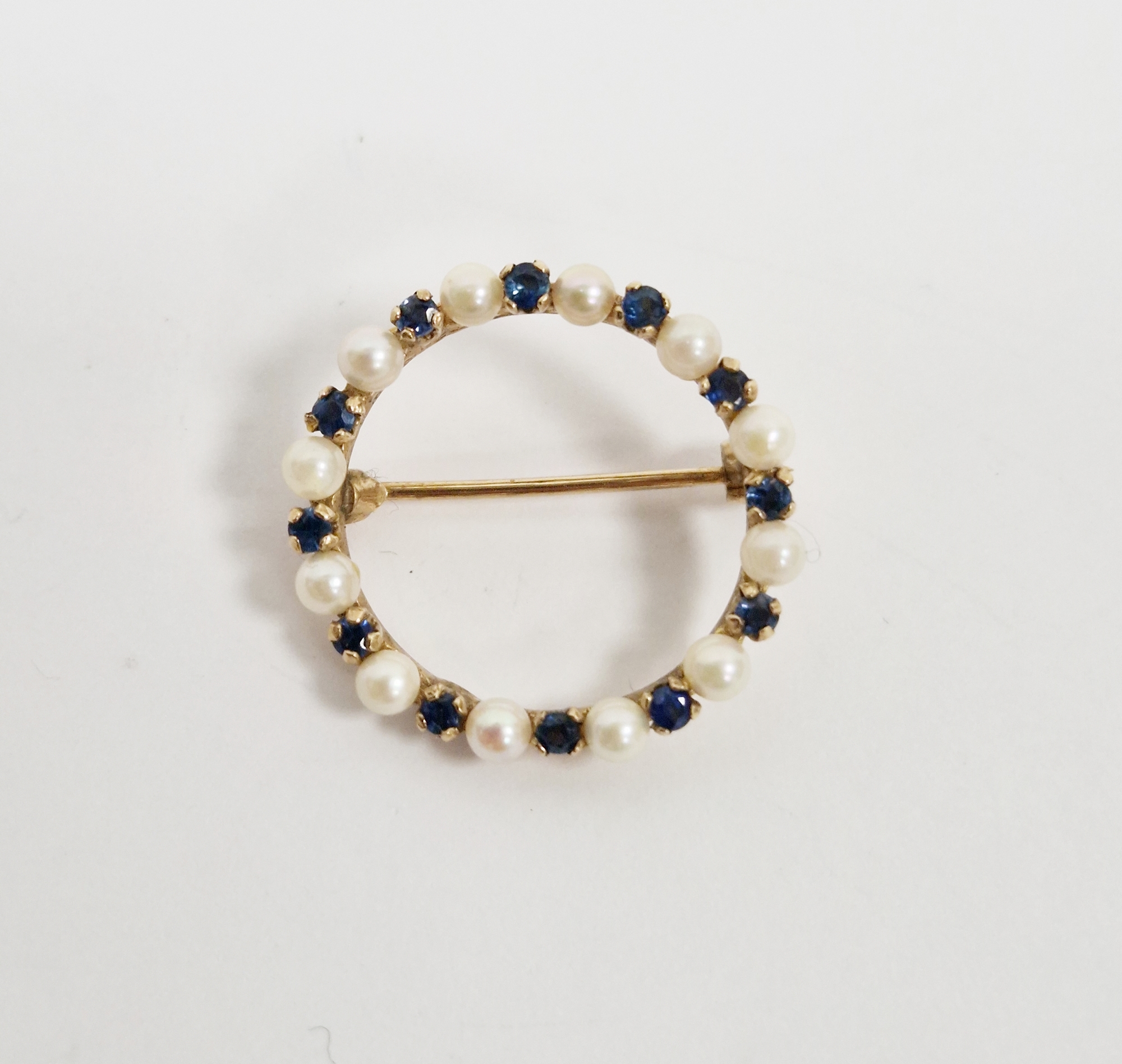 Modern 9ct gold circle brooch set with alternating sapphires and cultured pearls, 2.5cm diameter,