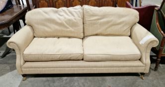 Modern cream upholstered three seater sofa, with scroll arms, on turned tapering front legs with