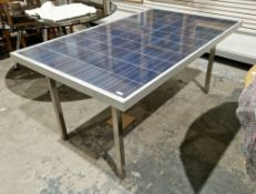 Modern dining table, the top formed from a solar panel mounted in an aluminium frame, on square