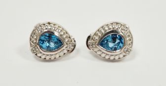 Pair of silver stud earrings set with a central teardrop blue topaz and with white sapphire details,