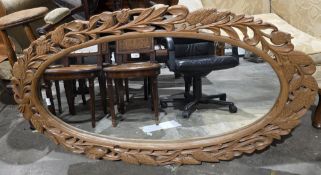 Modern oval mirror, the pine frame with pierced carving of pine cones and scrolling foliage, 135cm