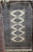 Pakistani-style cream ground bokhara rug with five central hooked lozenge medallion, each with