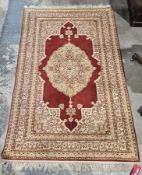 Persian style rug with central cream, beige and red foliate medallion, on a red ground within cream,