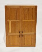 Hand-built oak cupboard comprising two pairs of panelled doors with rectangular dark walnut handles,