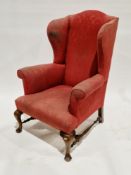 Wing armchair on mahogany cabriole supports with turned stretchers, upholstered in red  Condition