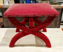 Red velvet upholstered dressing stool, the X-frame also upholstered in brass studded red fabric,