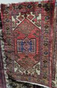 Iranian red ground rug with central geometric medallion on large lozenge, floral field and