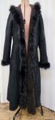 A black shearling full length coat with a fur trim to the hood, sides and cuffs, labelled Guaranteed
