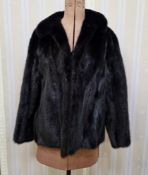 A black short mink jacket, half belt, bracelet sleeves labelled Faulkes Edgbaston Birmingham and a