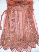 A 1920's pink chiffon dress - heavily beaded with bugle beads and sequins, with ribbons hip height