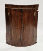 George III mahogany veneered bow-fronted hanging corner cabinet, the twin doors opening to a later