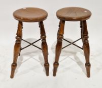 Pair of elm seated stools on turned supports, iron X-shaped stretchers, 54cm high x 46cm diameter (