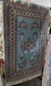 Persian style turquoise ground rug with central geometric medallion, stylized birds, multiple
