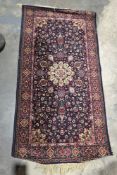 Persian style midnight blue ground rug with central floral motif on woven floral field, floral