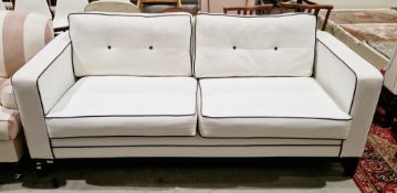 Contemporary two-seater sofa, upholstered in white fabric with black piping and black buttons to