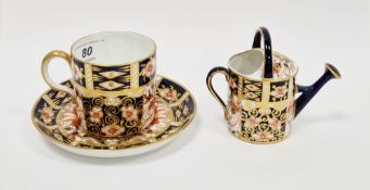 Derby imari pattern coffee-cup and saucer and a small model of a watering can, circa 1900, printed