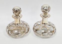 Pair of clear glass scent bottles with stoppers of squat form, with naturalistic scrolling white