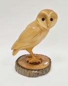 Wooden carved sculpture of a barn owl with glass effect eyes, mounted on a log cross-section base,
