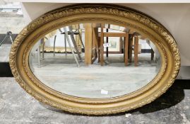 Oval wall mirror, the gilt frame with moulded leaf and berry decoration, the plate with bevelled