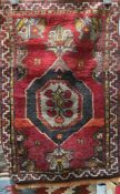 Small Eastern red ground rug with central elephant foot guls enclosing cherries, geometric spandrels