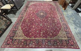 Large modern red ground carpet with central floral motif on floral field, floral spandrels and