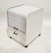 White laminate filing cupboard the upper section with a tambour door with a drawer below on castors,