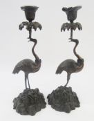 After Thomas Abbot pair bronze crane candlesticks, each with scroll decorated sconce, foliate drip