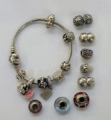 Pandora snake chain bracelet with a heart-shaped clasp, holding various silver and other charms