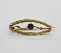 Late Victorian/Edwardian gold coloured metal and amethyst coloured stone bar brooch of elliptical