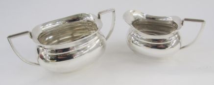George V silver cream jug and sugar basin, each oval with everted rim, shouldered angular handles,