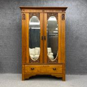A C.1900 Art Nouveau style satin walnut wardrobe having a moulded cornice above two carved doors
