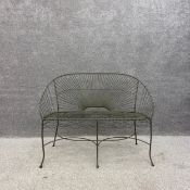 A vintage French style wrought iron and wire work garden tub form bench with a sunburst back and